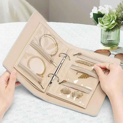 Beige jewelry organizer with gold jewelry pieces on a light surface.